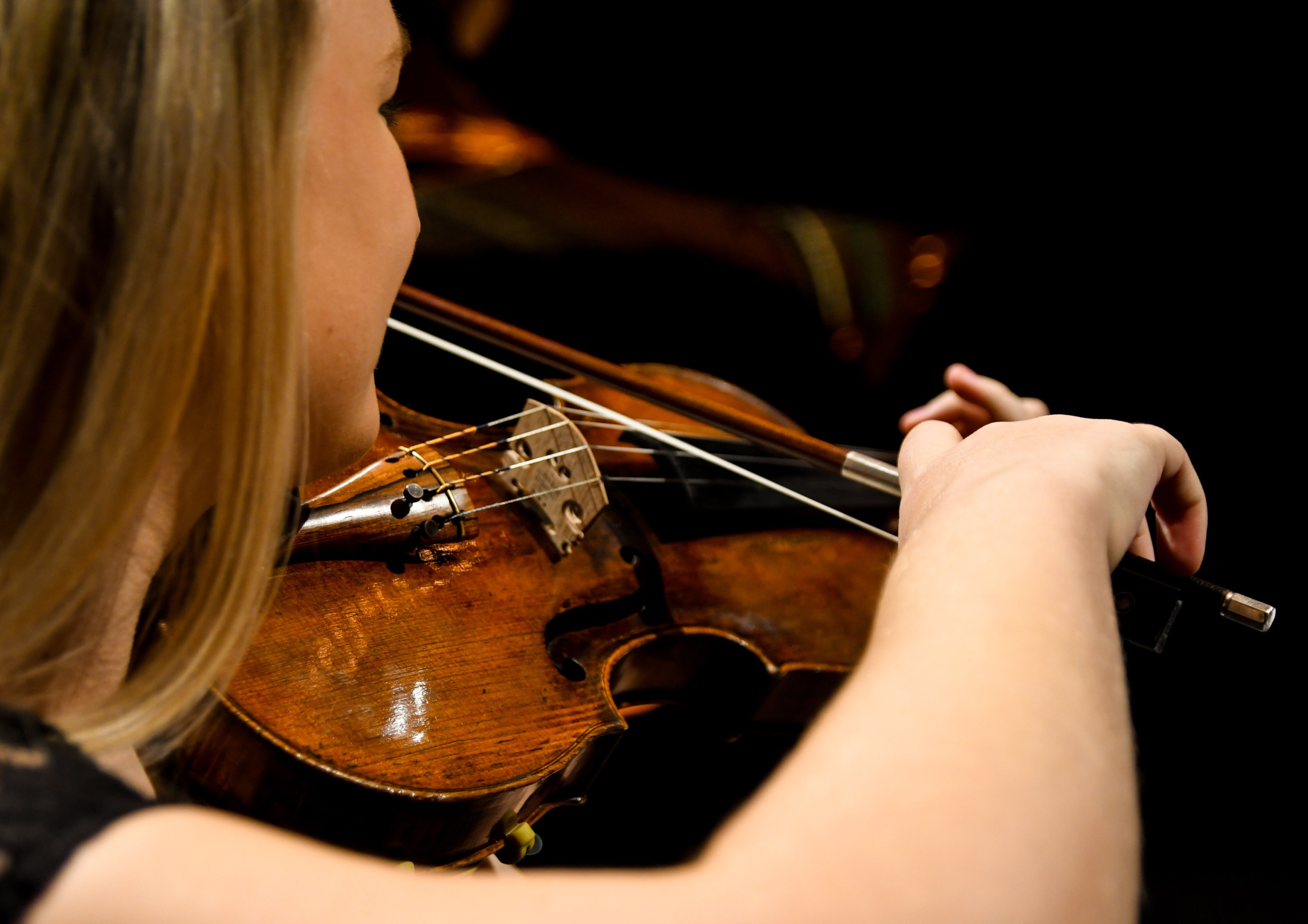 Blick über die Schulter einer Violinistin, die gerade ihr Instrument spielt